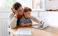 Mom with child in her lap typing on laptop.